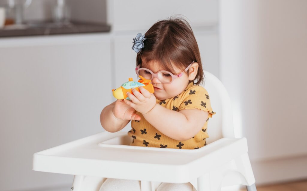 little baby girl weared eyeglasses playing with toys